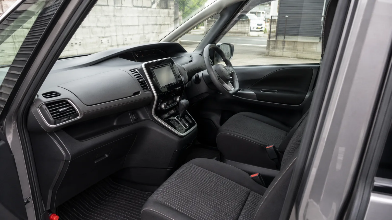 清掃を終えたミニバンの運転席まわり。ダッシュボードとドア内張り、黒いファブリックシート、フロアマットまで砂やホコリが残っておらず、艶出し剤で光らせていないマットな質感に整えてある