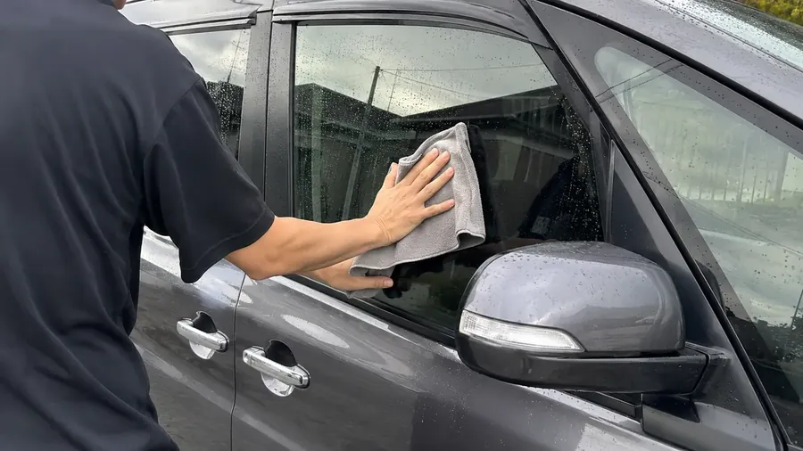 運転席側のドアガラスとミラーの周りを、マイクロファイバークロスで仕上げ拭きしているところ